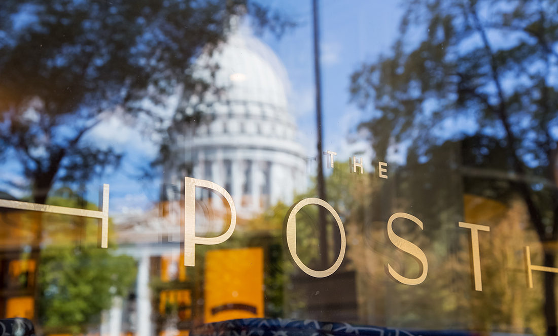 Window of The Post restaurant showing a reflection of the Wisconsin State Capitol